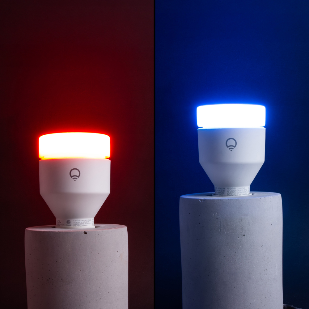 Two LIFX color changing smart light bulbs, one red and one blue, on concrete base lamps.