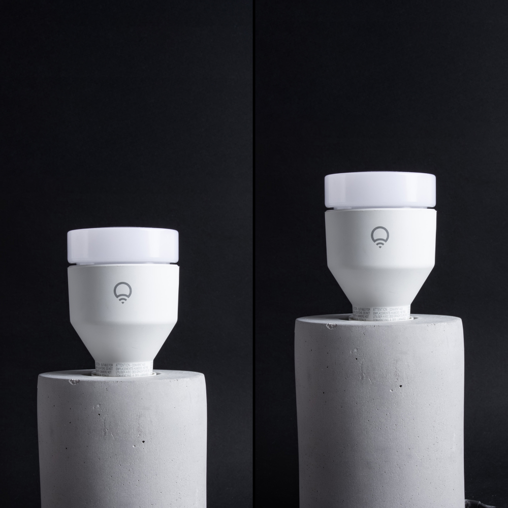 Two LIFX color changing smart light bulbs, one red and one blue, on concrete base lamps. Unlit.